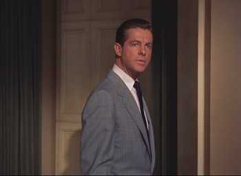Movie still from “Dial M for Murder” (1954), directed by Alfred Hitchcock – A man in a suit and tie standing in front of a door; Medium shot, Low angle