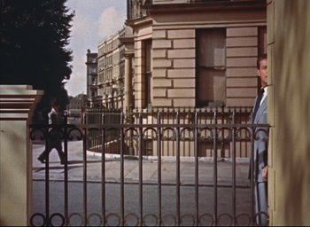 Movie still from “Dial M for Murder” (1954), directed by Alfred Hitchcock – A man standing in front of an iron fence; Wide shot, Low angle