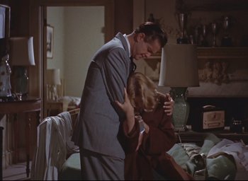 Movie still from “Dial M for Murder” (1954), directed by Alfred Hitchcock – A man and a woman in a room with a lamp; Medium shot, High angle