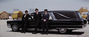Movie still from “Diamonds Are Forever” (1971), directed by Guy Hamilton – A group of men standing in front of a car; Wide shot, Low angle