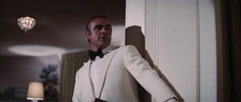 Movie still from “Diamonds Are Forever” (1971), directed by Guy Hamilton – A man in a white suit and a bow tie; Medium shot, Low angle