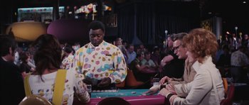 Movie still from “Diamonds Are Forever” (1971), directed by Guy Hamilton – A man wearing a colorful polka dot shirt playing a game of poker; Medium shot, Over the shoulder angle