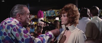 Movie still from “Diamonds Are Forever” (1971), directed by Guy Hamilton – A woman in a clown suit is holding a gun; Medium shot, Over the shoulder angle