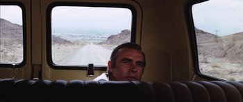 Movie still from “Diamonds Are Forever” (1971), directed by Guy Hamilton – A man sitting in a bus looking out the window; Medium shot, Over the shoulder angle