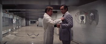 Movie still from “Diamonds Are Forever” (1971), directed by Guy Hamilton – Two men in white lab coats and a gray suit; Medium shot, Low angle