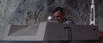 Movie still from “Diamonds Are Forever” (1971), directed by Guy Hamilton – A man sitting inside of an airplane with a bubble on top; Medium shot, Low angle