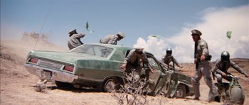 Movie still from “Diamonds Are Forever” (1971), directed by Guy Hamilton – A group of men standing next to an old car; Wide shot, Low angle