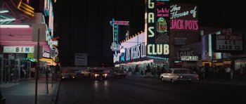 Movie still from “Diamonds Are Forever” (1971), directed by Guy Hamilton – Cars driving down the street in front of a neon sign at night; Extreme Wide shot, High angle