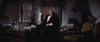 Movie still from “Diamonds Are Forever” (1971), directed by Guy Hamilton – A man sitting in a chair holding a piece of paper; Medium shot, Low angle