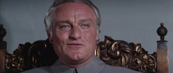 Movie still from “Diamonds Are Forever” (1971), directed by Guy Hamilton – An older man in a gray shirt and tie; Close Up shot, Low angle