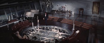 Movie still from “Diamonds Are Forever” (1971), directed by Guy Hamilton – A man standing in front of a clock in a room; Extreme Wide shot, High angle