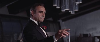 Movie still from “Diamonds Are Forever” (1971), directed by Guy Hamilton – A man in a tuxedo is holding something in his hand; Medium shot, Low angle