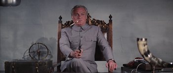 Movie still from “Diamonds Are Forever” (1971), directed by Guy Hamilton – An older man sitting in a chair holding a gun; Medium shot, Low angle
