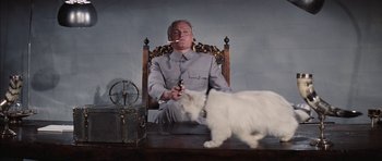 Movie still from “Diamonds Are Forever” (1971), directed by Guy Hamilton – A man sitting in a chair holding a gun and a white cat; Medium shot, Low angle