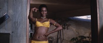 Movie still from “Diamonds Are Forever” (1971), directed by Guy Hamilton – A woman in a yellow bikini posing for a picture; Medium shot, Low angle