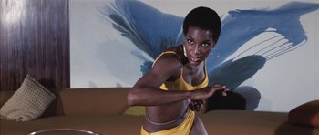 Movie still from “Diamonds Are Forever” (1971), directed by Guy Hamilton – A woman in a yellow bathing suit is posing for a picture; Medium shot, Low angle