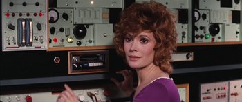 Movie still from “Diamonds Are Forever” (1971), directed by Guy Hamilton – A woman in a purple shirt is in front of a radio; Close Up shot, Over the shoulder angle
