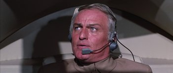 Movie still from “Diamonds Are Forever” (1971), directed by Guy Hamilton – An older man with a headset on looking at something; Close Up shot, Low angle