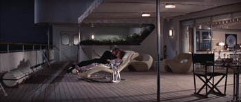 Movie still from “Diamonds Are Forever” (1971), directed by Guy Hamilton – A man and a woman laying on a chair on a deck; Wide shot, High angle