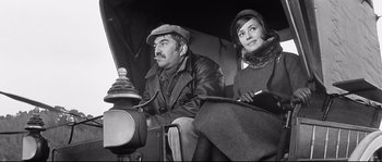 Movie still from “Diary of a Chambermaid” (1964), directed by Luis Buñuel – A man and a woman sitting next to a fire hydrant; Medium shot, Low angle