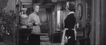 Movie still from “Diary of a Chambermaid” (1964), directed by Luis Buñuel – Two women are standing in a room talking; Medium shot, Low angle