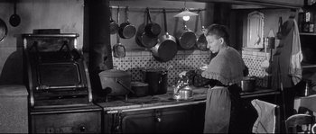 Movie still from “Diary of a Chambermaid” (1964), directed by Luis Buñuel – An old photo of a man cooking in a kitchen; Medium shot, High angle