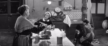 Movie still from “Diary of a Chambermaid” (1964), directed by Luis Buñuel – A woman sitting at a table with a tea pot in front of her; Medium shot, High angle