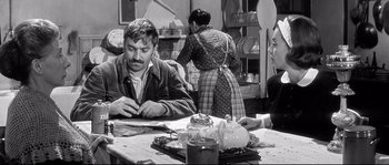 Movie still from “Diary of a Chambermaid” (1964), directed by Luis Buñuel – A group of people sitting at a table in a kitchen; Medium shot, Over the shoulder angle