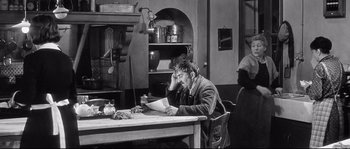 Movie still from “Diary of a Chambermaid” (1964), directed by Luis Buñuel – A man sitting at a table with a laptop in front of him; Medium shot, High angle