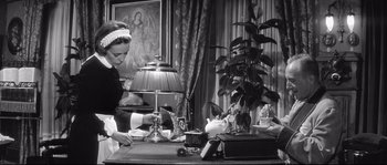 Movie still from “Diary of a Chambermaid” (1964), directed by Luis Buñuel – An old photo of a woman working at a desk; Medium shot, Low angle