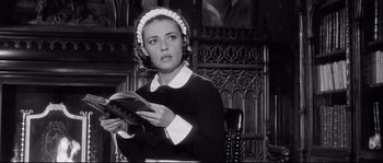 Movie still from “Diary of a Chambermaid” (1964), directed by Luis Buñuel – A black and white photo of a woman reading a book; Medium shot, Low angle