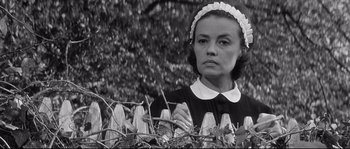 Movie still from “Diary of a Chambermaid” (1964), directed by Luis Buñuel – A woman wearing a black and white dress and a white hat; Close Up shot, Low angle