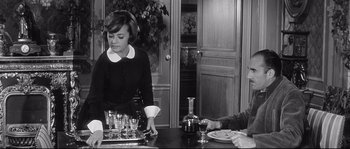 Movie still from “Diary of a Chambermaid” (1964), directed by Luis Buñuel – A man and a woman sitting at a dinner table; Medium shot, High angle