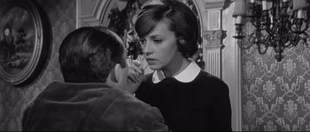 Movie still from “Diary of a Chambermaid” (1964), directed by Luis Buñuel – A woman is putting makeup on a man's face; Medium shot, Over the shoulder angle