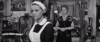 Movie still from “Diary of a Chambermaid” (1964), directed by Luis Buñuel – A woman in a maid's uniform and a woman in a black dress; Medium shot, Low angle