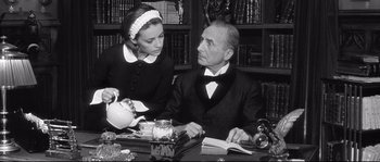 Movie still from “Diary of a Chambermaid” (1964), directed by Luis Buñuel – An older man and a young woman sitting at a table; Medium shot, Low angle