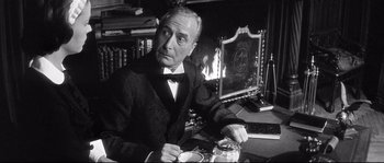 Movie still from “Diary of a Chambermaid” (1964), directed by Luis Buñuel – An older man sitting at a table with a cup of coffee; Medium shot, Over the shoulder angle