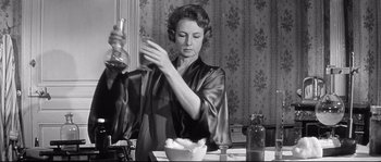 Movie still from “Diary of a Chambermaid” (1964), directed by Luis Buñuel – An old photo of a woman in a robe preparing a meal; Medium shot, Low angle