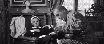Movie still from “Diary of a Chambermaid” (1964), directed by Luis Buñuel – An older man and a young woman sitting in a chair; Medium shot, Low angle