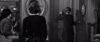 Movie still from “Diary of a Chambermaid” (1964), directed by Luis Buñuel – Two women standing in front of a large clock; Medium shot, Over the shoulder angle