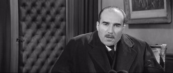 Movie still from “Diary of a Chambermaid” (1964), directed by Luis Buñuel – An old photo of a man in a suit and tie; Close Up shot, Low angle