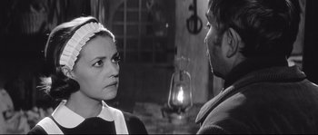 Movie still from “Diary of a Chambermaid” (1964), directed by Luis Buñuel – A man and a woman are standing next to each other in front of an oil lamp; Close Up shot, Over the shoulder angle