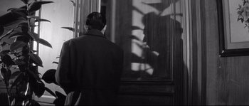 Movie still from “Diary of a Chambermaid” (1964), directed by Luis Buñuel – A man standing in front of a window looking at himself; Medium shot, Low angle