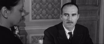 Movie still from “Diary of a Chambermaid” (1964), directed by Luis Buñuel – A black and white photo of a man in a suit and tie; Close Up shot, Low angle