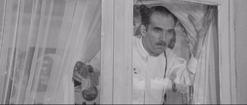 Movie still from “Diary of a Chambermaid” (1964), directed by Luis Buñuel – An old photo of a man looking in a mirror; Medium shot, Low angle