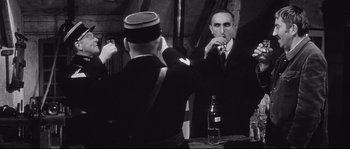 Movie still from “Diary of a Chambermaid” (1964), directed by Luis Buñuel – A man in a suit and tie is taking a picture of another man in a suit and tie; Medium shot, Over the shoulder angle