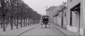 Movie still from “Diary of a Chambermaid” (1964), directed by Luis Buñuel – Two people are riding in a horse drawn carriage down the street; Wide shot, High angle