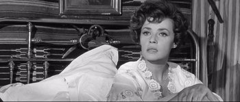 Movie still from “Diary of a Chambermaid” (1964), directed by Luis Buñuel – A black - and - white photo of a woman in front of an old car; Close Up shot, Low angle