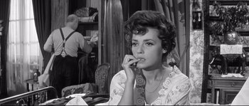Movie still from “Diary of a Chambermaid” (1964), directed by Luis Buñuel – A black and white photo of a woman sitting at a table; Close Up shot, Over the shoulder angle