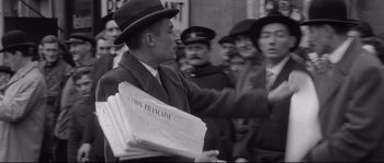 Movie still from “Diary of a Chambermaid” (1964), directed by Luis Buñuel – A man in a hat is holding a newspaper; Medium shot, Over the shoulder angle
